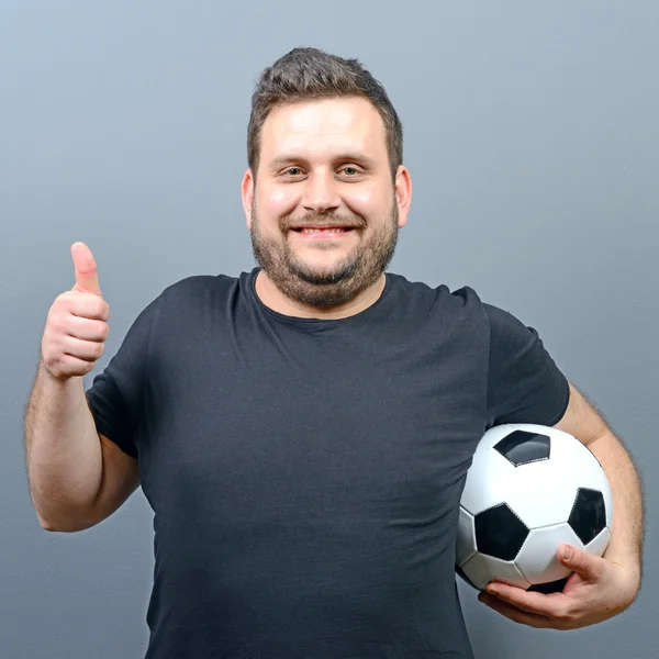 Portrait of chubby man holding football and showing thumb up - F
