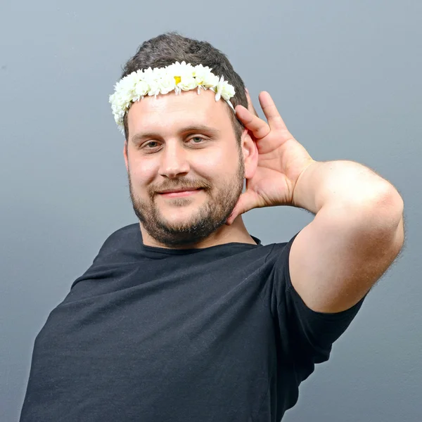 Portrait of funny chubby man wearing flower wreath on head and b