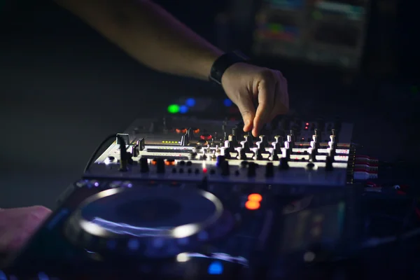 Dj hands on equipment deck and mixer with vinyl record at party