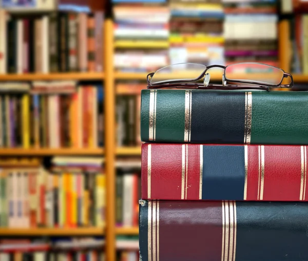 Library concept - Books and glasses against book shelves