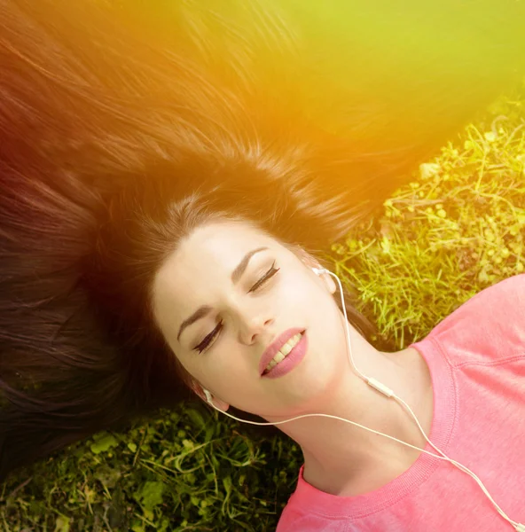 Girl listening to music while lying on grass during summer day