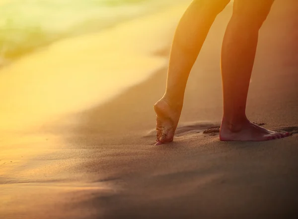 Beach travel - woman walking on sand beach leaving footprints in