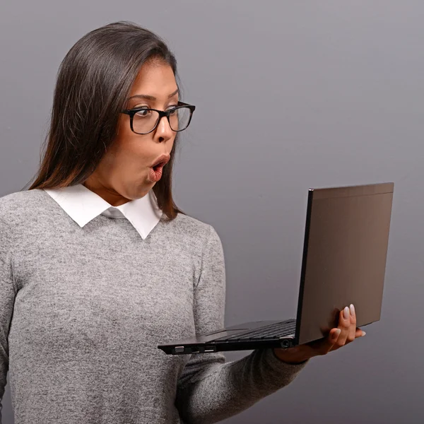 Portrait of woman in shock what she sees at her laptop against g