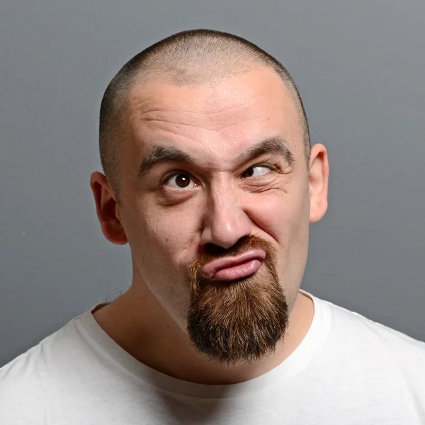 Portrait of a man making funny face against gray background