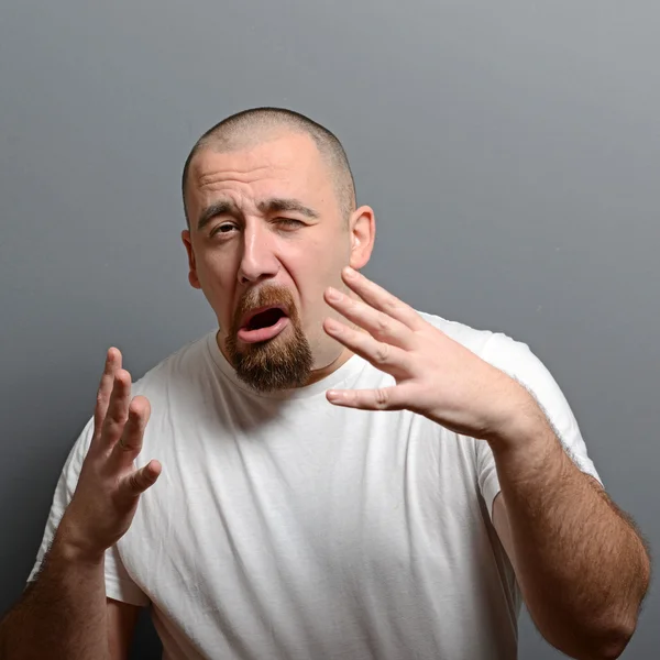 Portrait of a man making funny face against gray background