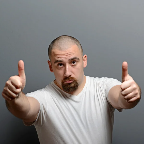 Portrait of a man showing thumb up or ok sign against gray backg