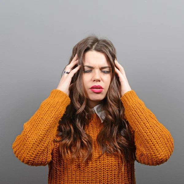 Portrait of woman with headache against gray background