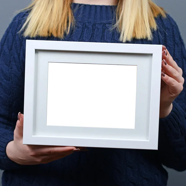 Portrait of smiling woman holding blank photo frame against gray