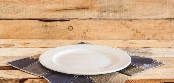 Clean plate with napkin on wooden background.