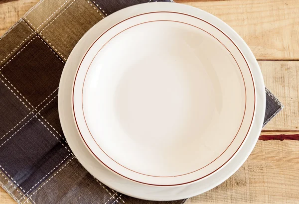 Clean plate with napkin on wooden background.