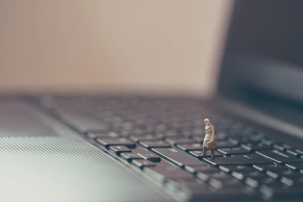 Miniature businessman walking on the laptop