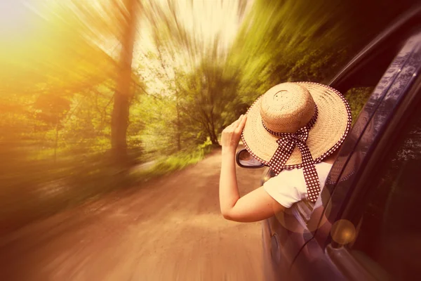 Girl with hat in the window of the car