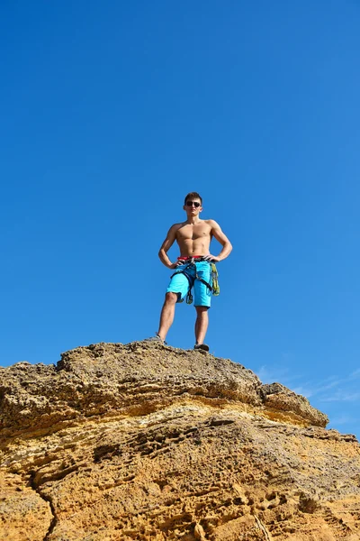 Athletic climber man standing back on top mountain