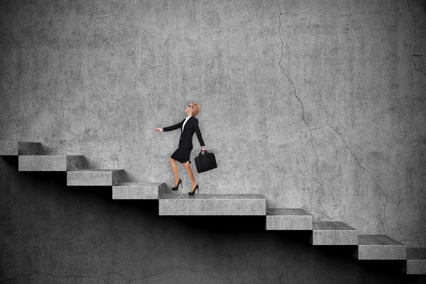 Businesswoman with briefcase climbs the stairs. Success concept
