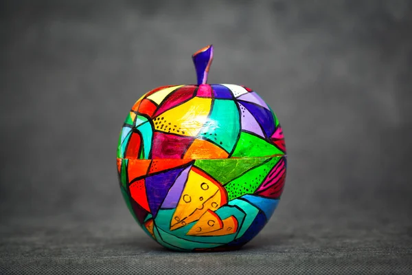 Decorative apple, made of wood and painted by hand paints on abstract black background. contemporary art, modern art