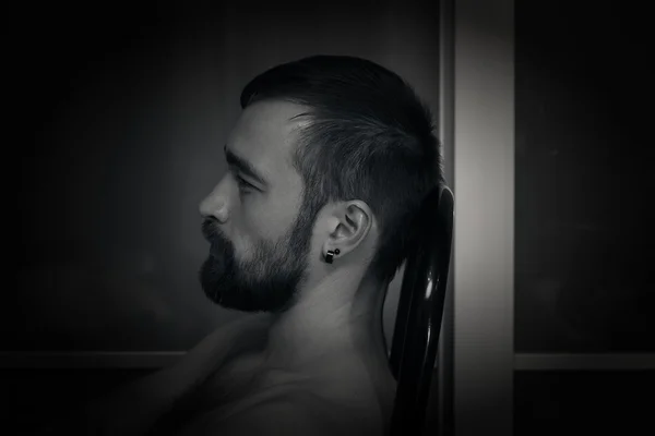 Portrait of a man in profile closeup. Brutal macho with a beard.