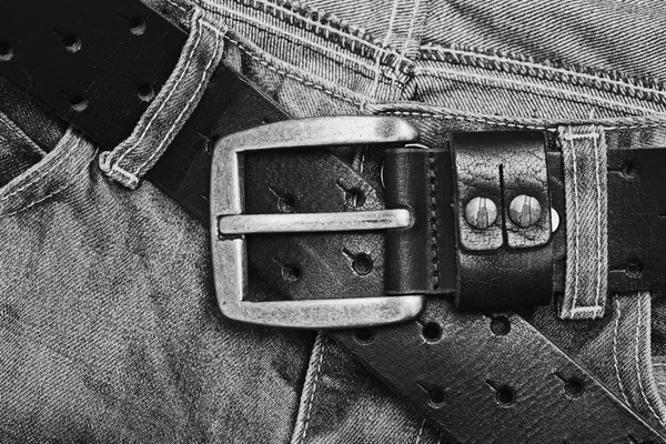 Jeans with leather belt and buckle close up top view. Background texture jeans