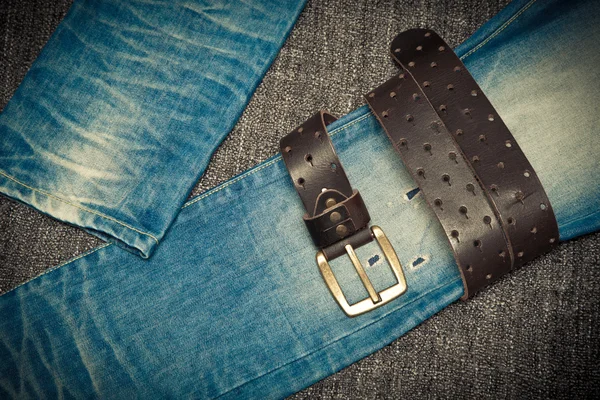 Fashion trend: blue shabby jeans and a leather belt with a buckle