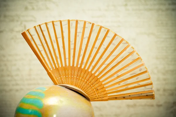 Folding hand fan made of wood in a vase