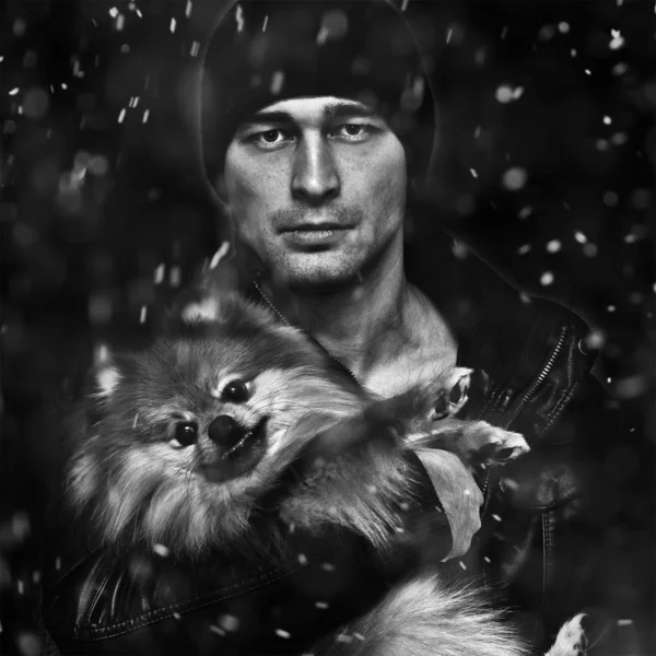 Portrait of a man with a dog on a black background, the snow falls