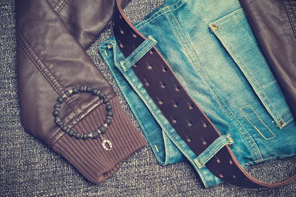 Details of clothes: jeans with a belt, leather jacket, bracelet on the arm