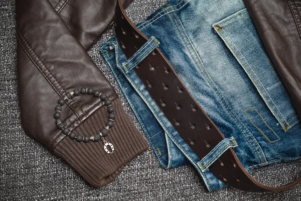 Youth clothes: jeans with a leather belt, leather jacket, jewelry bracelet on the arm