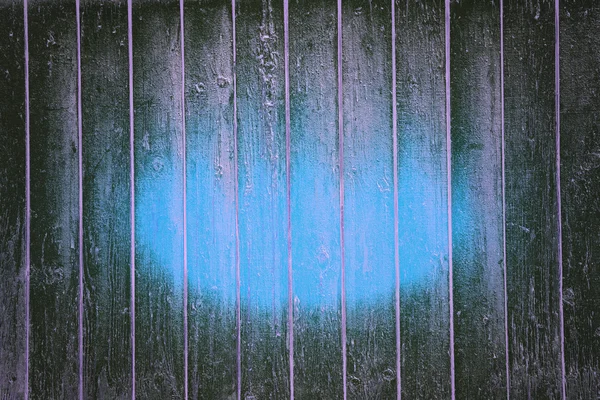 Abstract background of textured dark wooden boards with a blue glow in the center