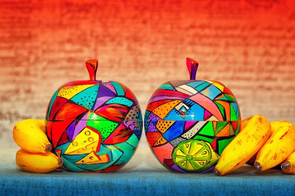 Decorative wooden apples and bananas on bright abstract background. Apples are made and painted by hand