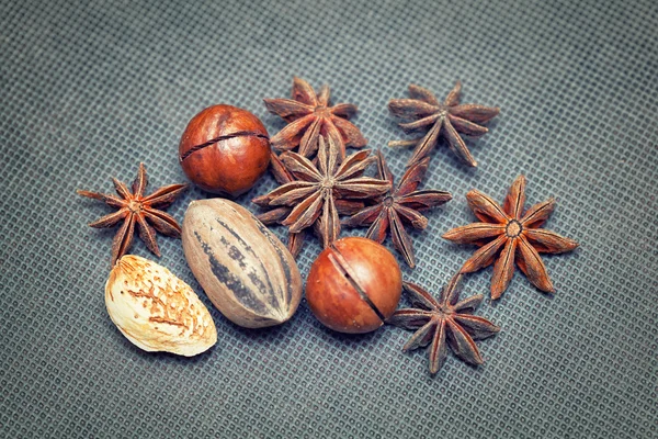 Food concept from nuts and spices: almonds, pecans, macadamia nuts, star anise on black background