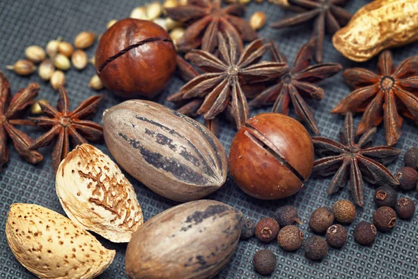 Nuts and spices - pecans, almonds, macadamia, peanuts, star anise, black allspice, grains of sesame seeds on dark background