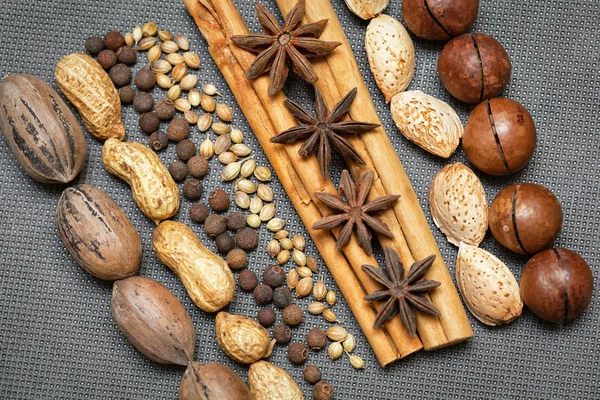 Creative design of nuts and spices, cinnamon sticks, pecans, almonds, macadamia, peanuts, star anise, black allspice, grains of sesame seeds