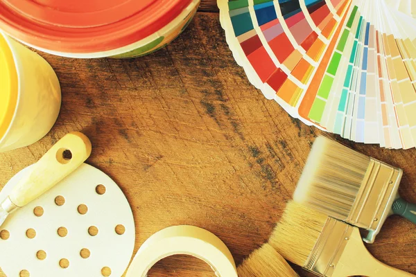 Various painting tools and color guide on wooden background