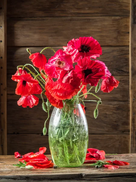 Bouquet of poppy flowers in the vase on the wooden table.