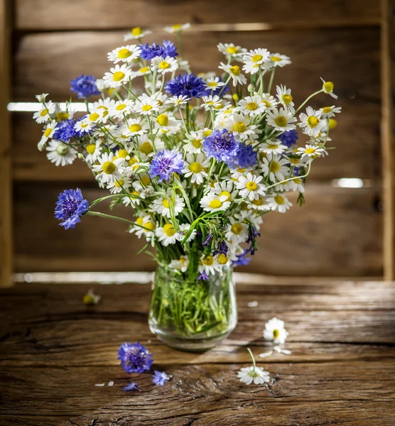 Bouquet of chamomiles and cornflowers in the vase on the wooden