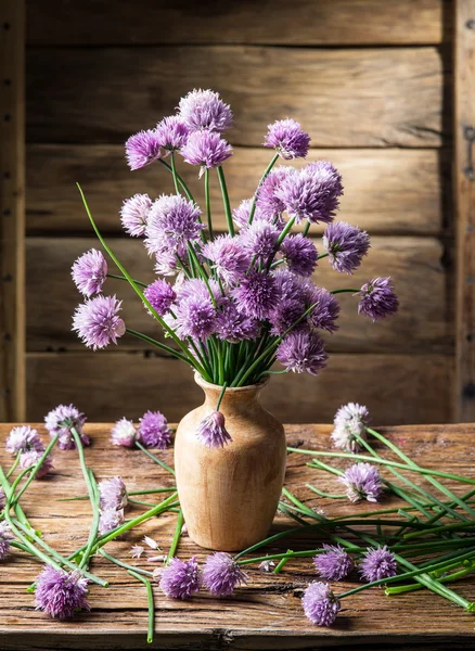 Bouquet of onion (chives) flowers in the vase on the wooden tabl