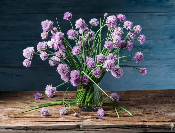 Bouquet of onion (chives) flowers in the vase on the wooden tabl