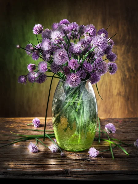 Bouquet of onion (chives) flowers in the vase on the wooden tabl