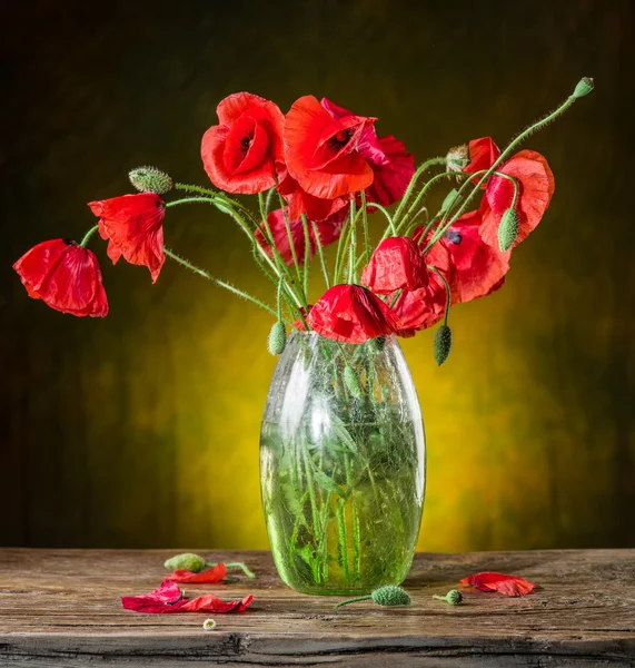 Bouquet of poppy flowers in the vase on the wooden table.