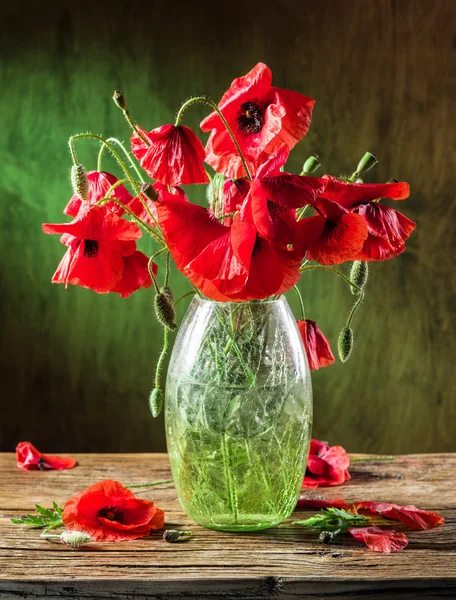 Bouquet of poppy flowers in the vase on the wooden table.