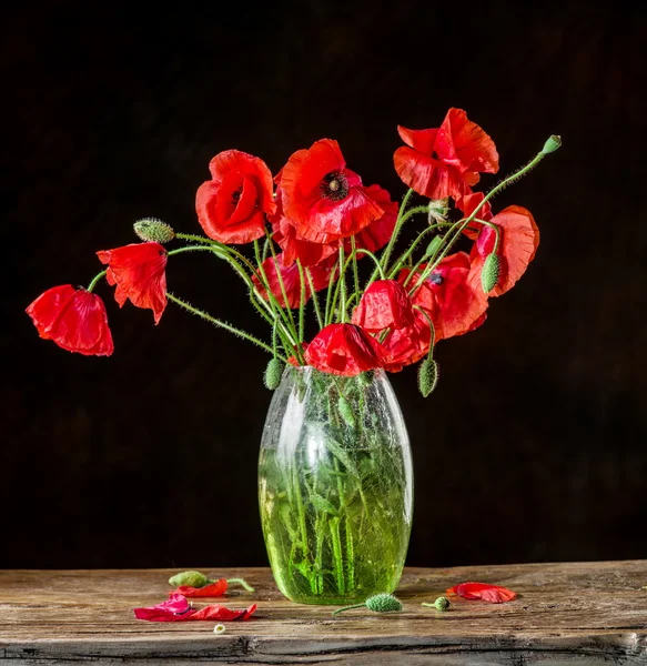 Bouquet of poppy flowers in the vase on the wooden table.