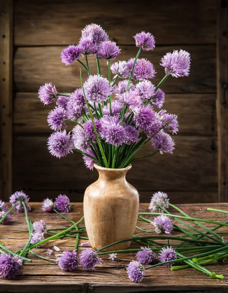 Bouquet of onion (chives) flowers in the vase on the wooden tabl