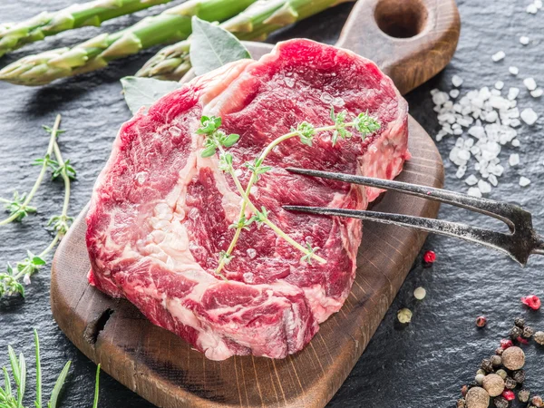 Rib eye steak with spices on the black background.