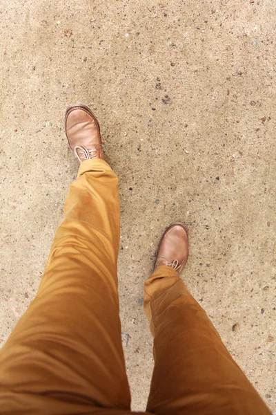 Man\'s feet in shoes walking on a park lane.