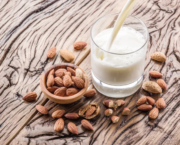 Almond nuts and milk on wooden table.