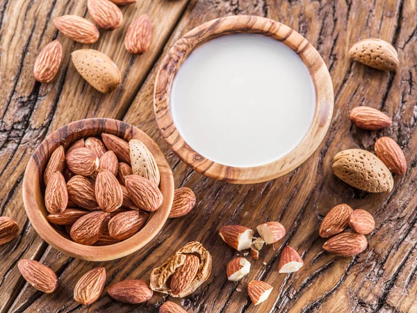 Almond nuts and milk on wooden table.