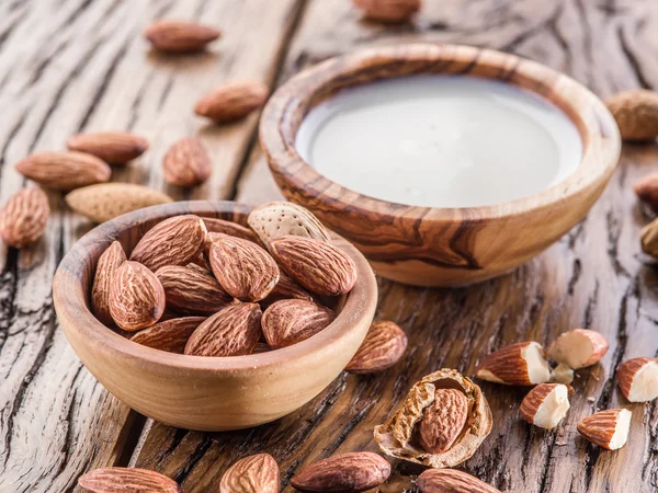 Almond nuts and milk on wooden table.