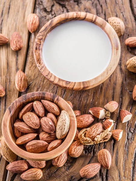 Almond nuts and milk on wooden table.