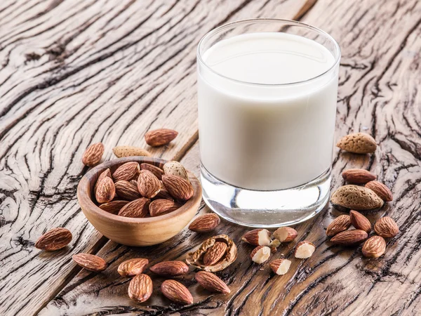 Almond nuts and milk on wooden table.