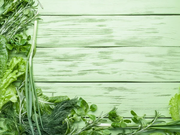 Green herbs on the green wooden background.