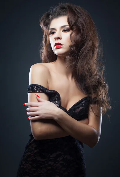 Beautiful natural curly brunette hair, portrait of an young girl with red lips isolated on dark